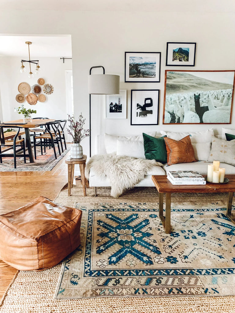 Layered rugs styled in a modern living room with a neutral jute base and a colorful Moroccan kilim on top