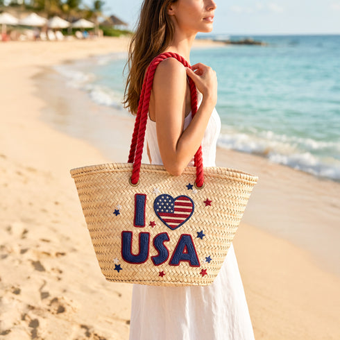 Handwoven straw beach tote with “I Love USA” embroidery and American flag heart, natural palm leaf basket with red rope handles, stylish patriotic travel and summer bag for women