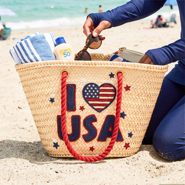 Handwoven straw beach tote with “I Love USA” embroidery and American flag heart, natural palm leaf basket with red rope handles, stylish patriotic travel and summer bag for women