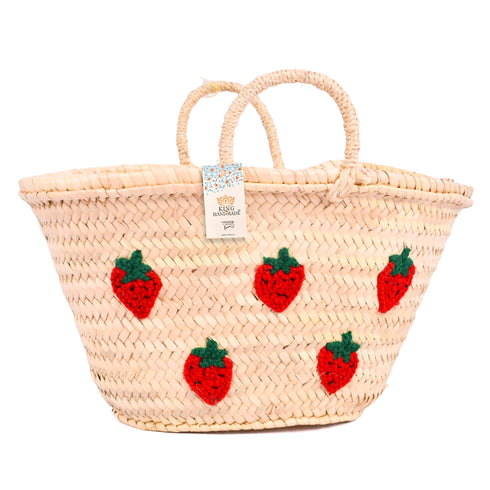 Hand-embroidered straw basket with multiple red strawberries, green leaves, and natural palm leaf texture