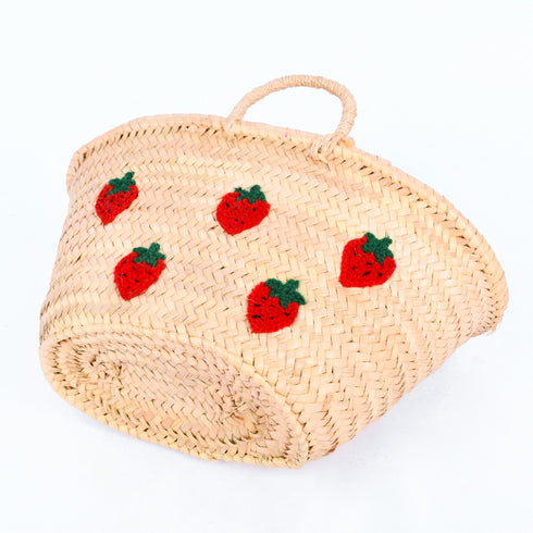 Hand-embroidered straw basket with multiple red strawberries, green leaves, and natural palm leaf texture