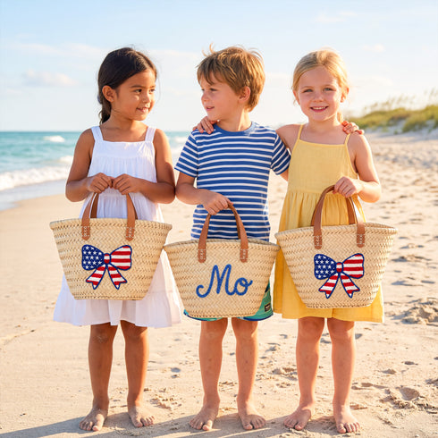 Personalized USA kids straw basket with embroidered American flag bow, small handwoven palm leaf tote with leather handles, custom name on back, patriotic children’s beach and birthday gift bag