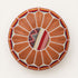 Top view of a stuffed tan round fusion pouf with leather panels, white beaded stitching and a center of red, gold and cream Amazigh Berber motif fabric