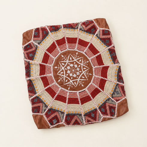 Unstuffed dark tan round fusion pouf cover laid flat, showing red, cream and white Moroccan Amazigh Berber embroidered motifs