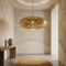 Handmade Moroccan brass pendant light with intricate perforated design casting elegant shadow patterns in a minimalist entryway