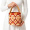 Boho raffia bucket bag with orange embroidery and wooden bead handle styled with a white eyelet dress