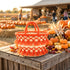 Moroccan orange tassel straw basket with gold bead details on a wooden fall farm stand surrounded by pumpkins and autumn leaves
