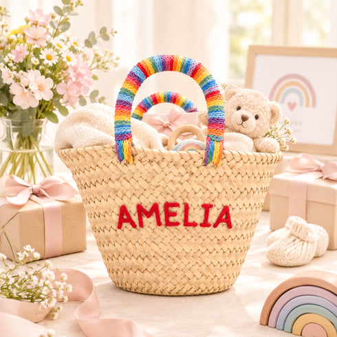 Personalized rainbow baby shower basket with the name AMELIA embroidered in red and rainbow handles, styled with baby gifts
