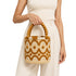 Woman holding handmade raffia bucket bag by beaded goldenrod handle with cream linen trousers, Moroccan straw handbag