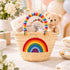 Rainbow baby gift basket with embroidered rainbow icon holding a teddy bear, muslin blanket, booties and gift box