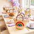 Rainbow baby shower favor baskets filled with guest gifts on a pastel party table with balloons and flowers
