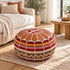 Tan round Moroccan pouf with leather top and Amazigh Berber motif fabric styled on a woven rug beside a cream sofa in a bright living room