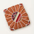 Unstuffed tan round fusion pouf cover laid flat, showing leather panels with a center of red, cream and gold Moroccan Amazigh Berber motif fabric