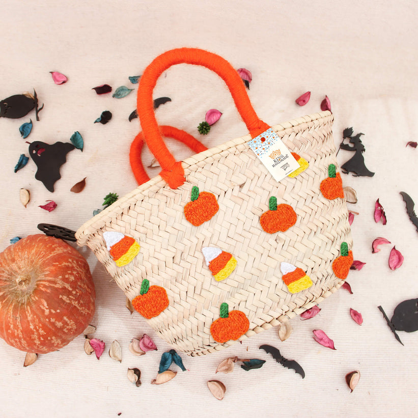 A bright orange Halloween tote bag decorated with candy corn and pumpkin patterns.