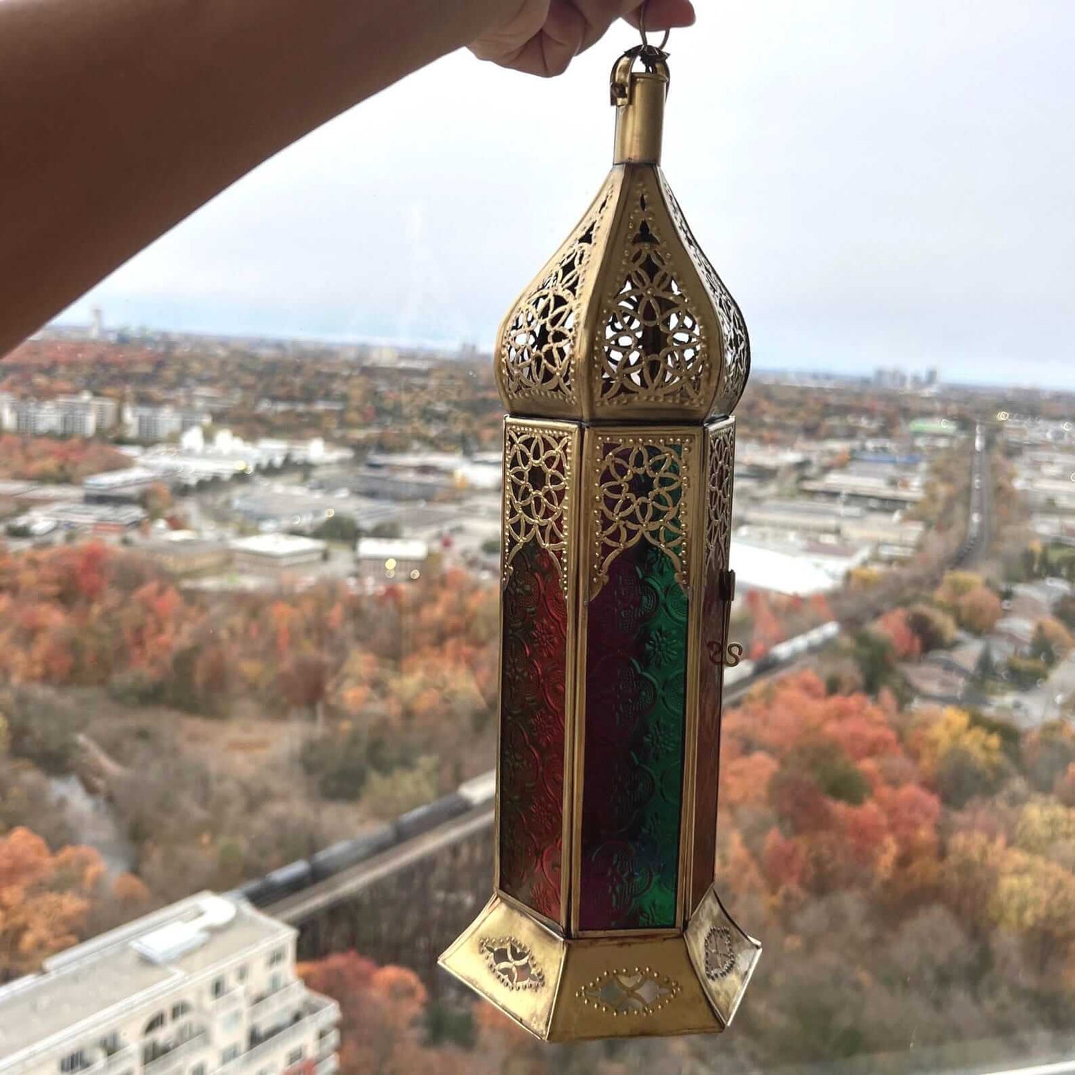 Large Moroccan brass lantern with colorful glass inserts casting intricate shadows