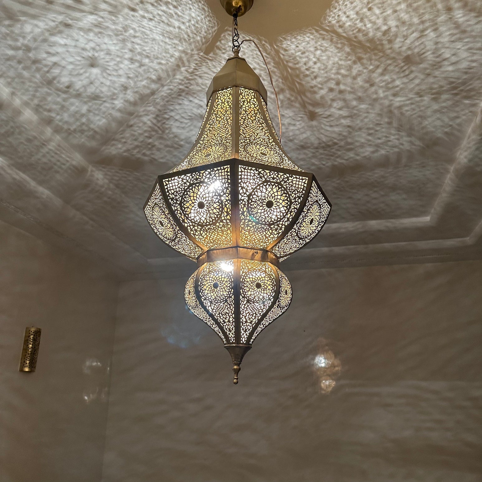 Intricate brass Moroccan chandelier featuring silver and bronze finishes, suspended in a modern living room