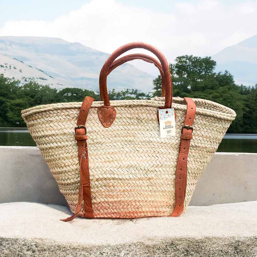 A woven palm leaf market bag with long handles