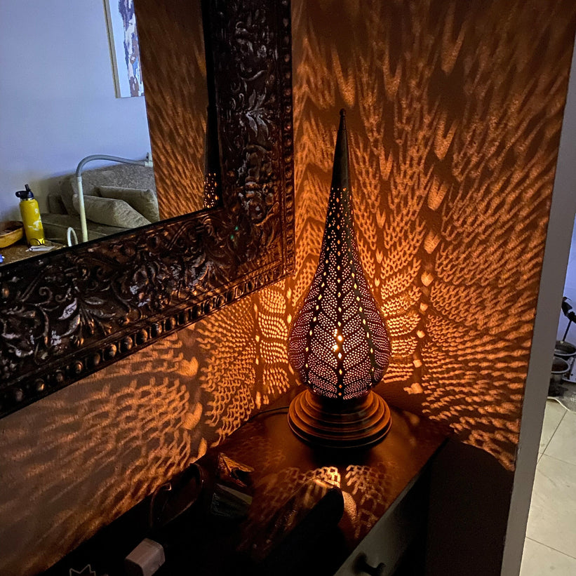 A close-up view of a beautifully crafted Moroccan-style pendant light, showing intricate metalwork details.