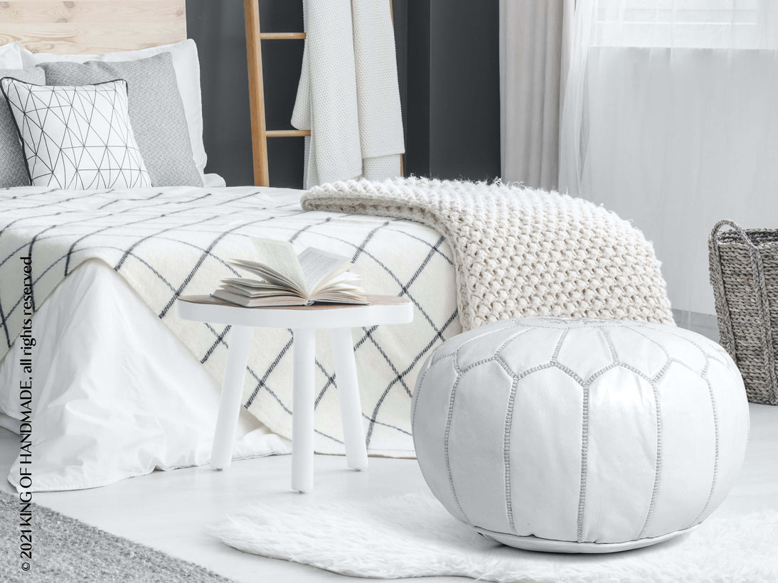 White Moroccan leather ottoman pouf in a bedroom setting